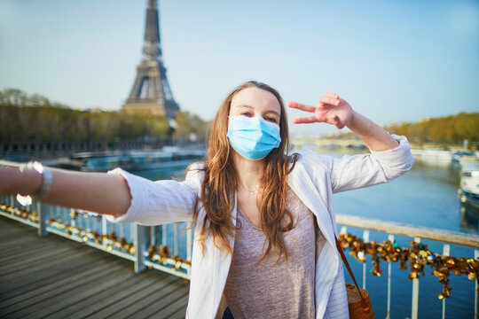 Young girl standing near the Eiffel tower in Paris and wearing protective face mask during coronavirus outbreak