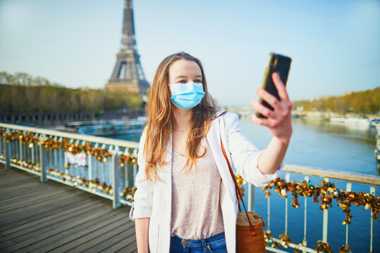 Young girl standing near the Eiffel tower in Paris and wearing protective face mask during coronavirus outbreak