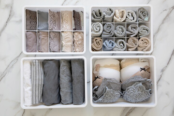 Womans underwear, pajamas and socks neatly folded and placed in closet organizer drawer divider on...