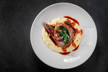 Baked beef tongue with mashed potatoes and sauce on a white plate. British cuisine, top view