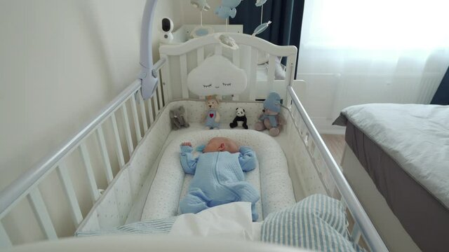 Adorable baby boy sleeping in a crib lying in baby pod nest newborn cocoon. High quality 4k footage