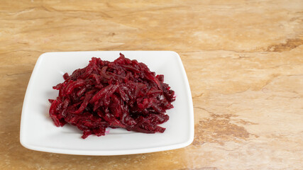 Obraz na płótnie Canvas Bowl of grated red beet on table