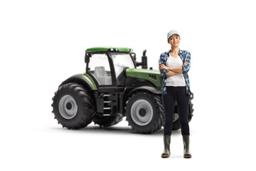 Full length portrait of a young female farmer posing with crossed arms in front of a tractor