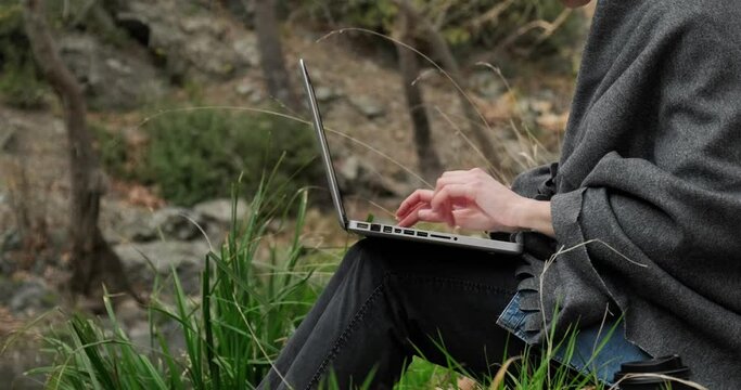 Close up side view of woman working in laptop outdoors in the park, freelancer working in forest, fast 5g internet connection.