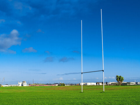 Tall goal post for Irish National sport rugby, hurling, gaelic football and camogie on a green training pitch, blue cloudy sky. Galway city and port in the background. South park area