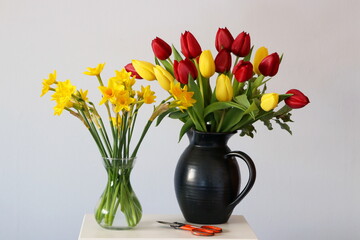 A gift of tulips and daffodils arranged in vases.