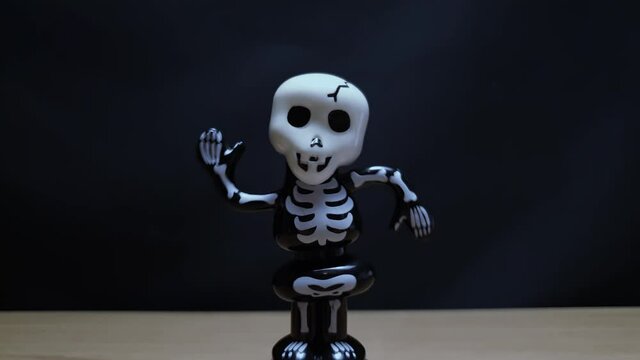Toy skeleton dancing on black background