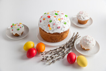 Easter cakes and colorful Easter eggs with willow branches on a white background. Homemade cakes for celebrating Easter.
