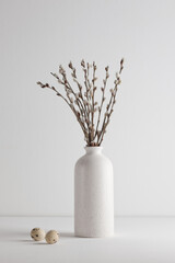 Easter eggs and a bouquet of willow trees in a vase on a white background