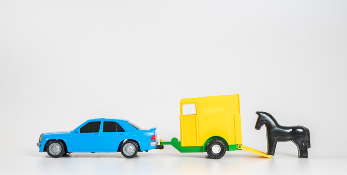 Children's toy plastic car isolated on white background. A multicolored passenger car with a horse trailer.