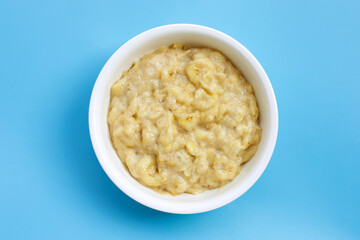 Mashed Bananas in bowl on blue background.
