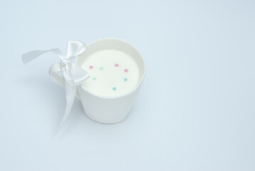 Fototapeta na wymiar White cup of milk with a bow on a white background