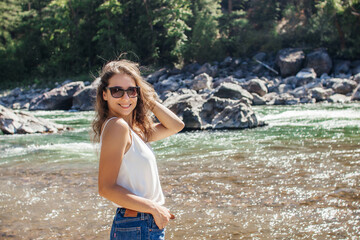 A young woman walks along a mountain river in the forest.Beautiful landscape with mountains,forest,and river with large rocks on a sunny summer day.Rest Area, I-90, Alberton, Montana, USA