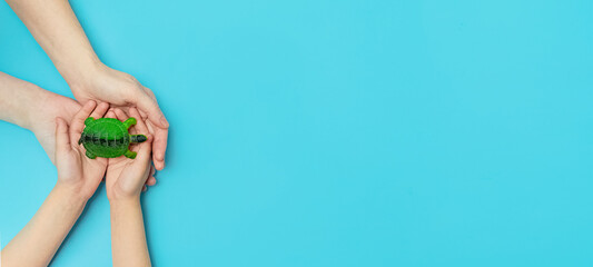 World turtle day and Ocean environmental day.A small turtle in the arms of a mother and daughter on a blue background