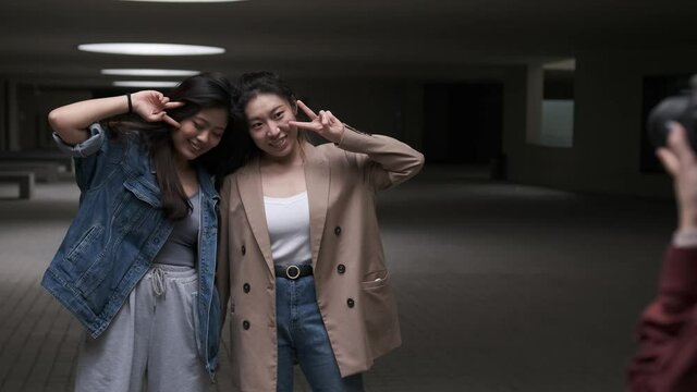 Two young asian women posing to the camera while the photographer taking some photos