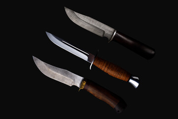 Set of knifes made of Damascus steel with a wooden handle on a isolated dark background