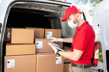 Male courier using a tablet while unloading a delivery truck