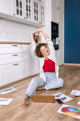 Attractive female freelancer or student stretching while working or studying, sitting on the floor at home. Young business woman making financial report or presentation, take a little break for rest