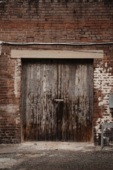 Fototapeta na wymiar Old grunge wooden door with dark red-brown brick surrounding