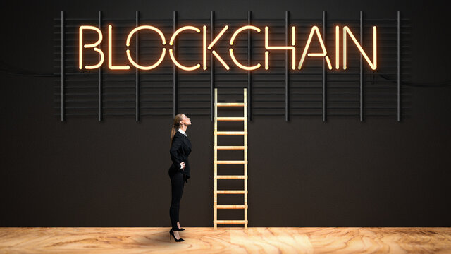 businesswoman looking at neon message BLOCKCHAIN on a black wall