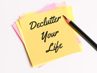 Inspirational and motivational quote. Phrase Declutter Your Life written on sticky note with a pencil.
