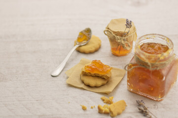 Selective focus to homemade cookies with fruit confiture and glases jar on the table.