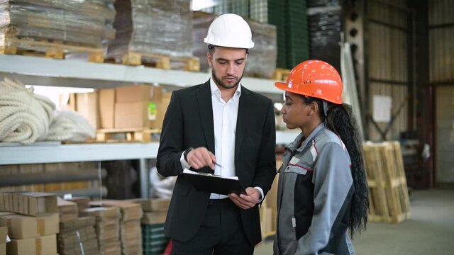 young manager and a warehouse worker discuss the availability of goods, production processes, technological features of the conveyor