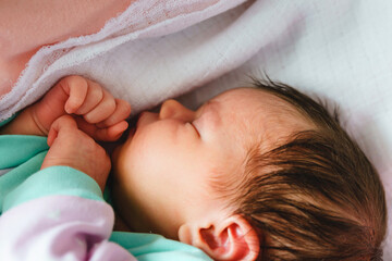 Close up on newborn caucasian baby sleeping in bed at home on first day of her life - cute little infant girl sleep peacefully