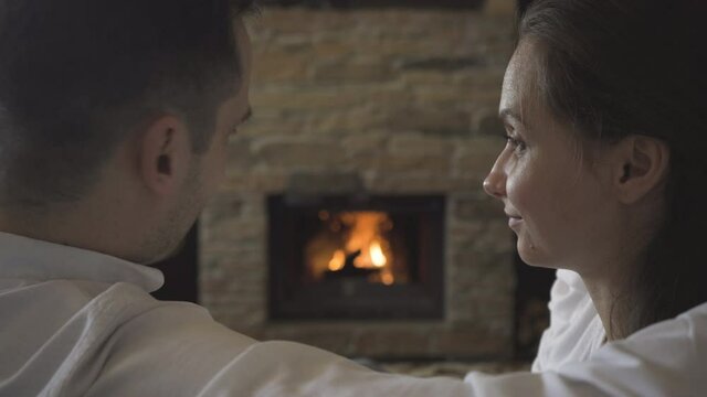 A couple in love is kissing by the fireplace, in which a fire is burning
