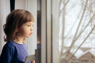 Toddler Girl Looking Out the Window at Home