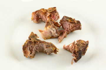 Close up of lamb chop bones with most of meat eaten  left over on white plate