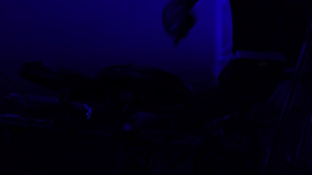 Professional musician playing drums and percussion cymbals in a dark smoky studio with blue lights. Close up of the drummer torso pounds on the drum kit. Rock concert, live performance. Silhouette.