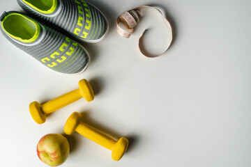Gym and workout, 
sports shoes, sneakers, Healthy lifestyle concept foto. Flat lay of sport. Athlete's set with centimeter tape, green apple and dumbbells on a grey background