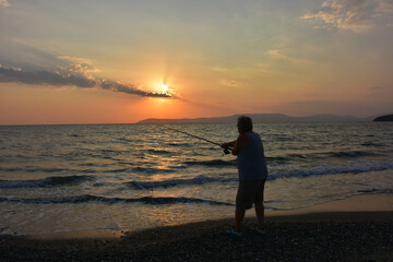 Fototapeta na wymiar A fisherman fishing at sunset