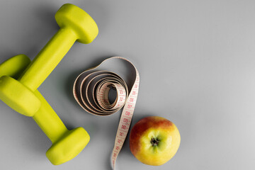 Gym and workout, Healthy lifestyle concept foto. Flat lay of sport. Athlete's set with centimeter tape, green apple and dumbbells on a grey background with space for text