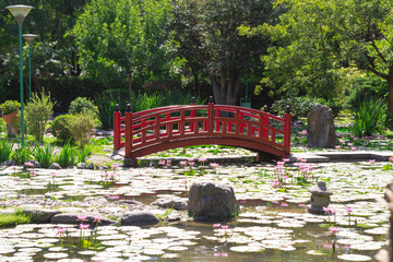 Little red bridge in a city park on a sunny day.