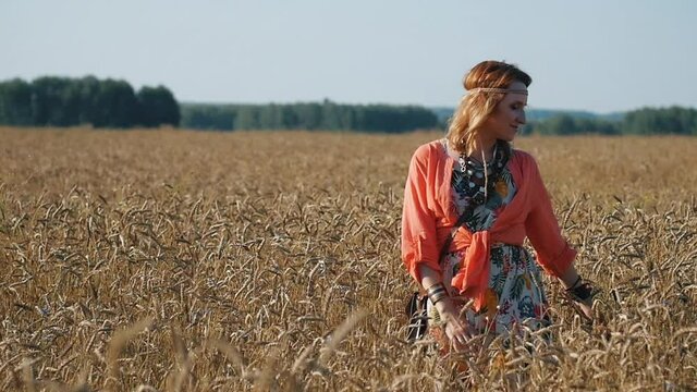 Attractive woman aged boho style.Portrait of blonde hippie near tree on a sunny day. Woman in boho style on the background of a wheat field