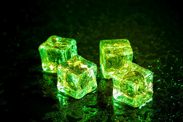 Green ice cubes reflection on black table background.