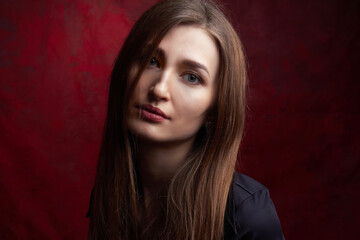 Fototapeta premium Portrait of a young woman with long brown hair, on a red textured background