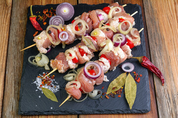 Raw pieces of pork shish kebab in marinade with pepper, onion,bay leaf.Pork shish kebab, ready to cook, barbecue, on an old wooden table.Rustic style.Selective focus.