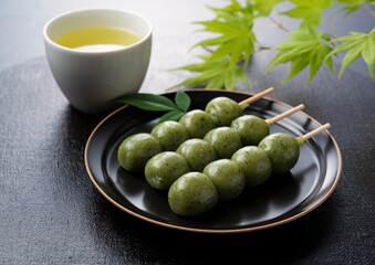 Kusadango dumplings and green tea set against a black background