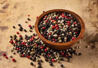 Pepper mix. Black, red, white, and green peppercorns on an old cutting board.