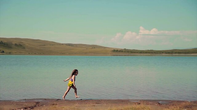 the girl is trampling in the water near the river. a child plays by the pond