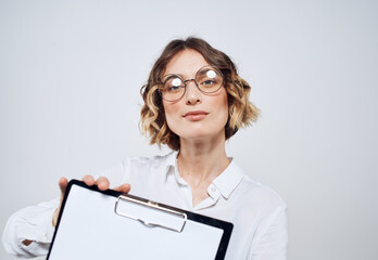 Naklejka premium Business woman holds in her hands a folder with a white sheet on a light background
