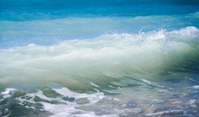 Turquoise blue sea wave crashes on a pebble shore, nature background and texture