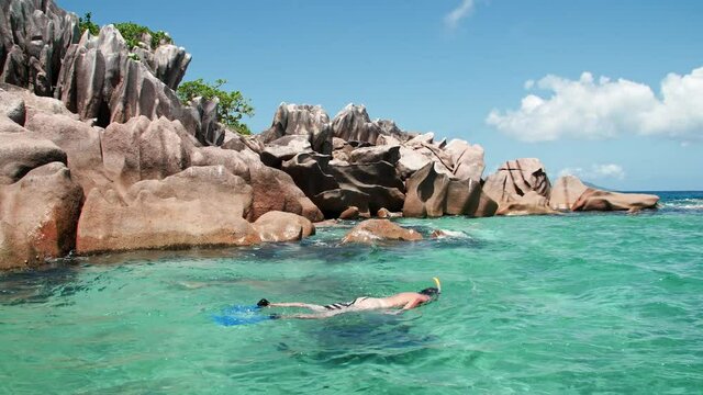 Snorkeling tourist in Seychelles Praslin, La Digue with Granite rock formations turquoise blue water of Indian Ocean paradise island honeymoon vacation hotspot destination