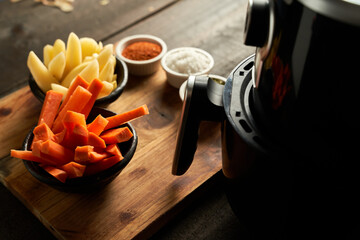 Cooking potatoes and carrot sticks with spices in an air fryer