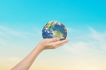 Globe in hands over blue sky background. Save of earth. Elements of this image furnished by NASA