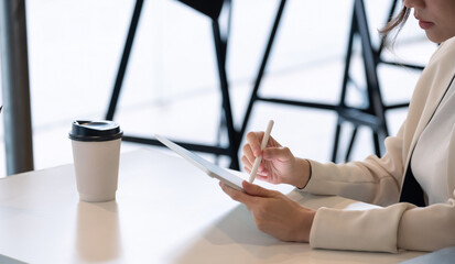 Close up businesswoman holds pen stylus drawing on digital tablet on workplace.