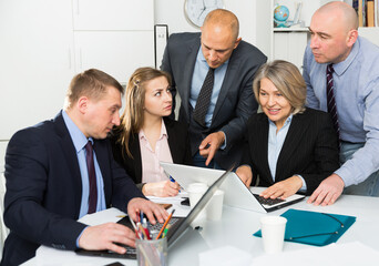 Successful coworkers engaged in business activities at common table in office